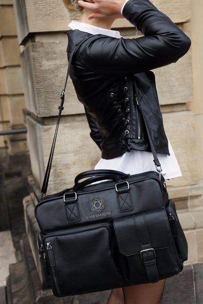 Seitliche Aufnahme der Kameratasche Aurora in schwarz. Eine Frau trägt diese mit dem Tragegurt über ihre Schulter und hat ihre rechte Hand im Haar.